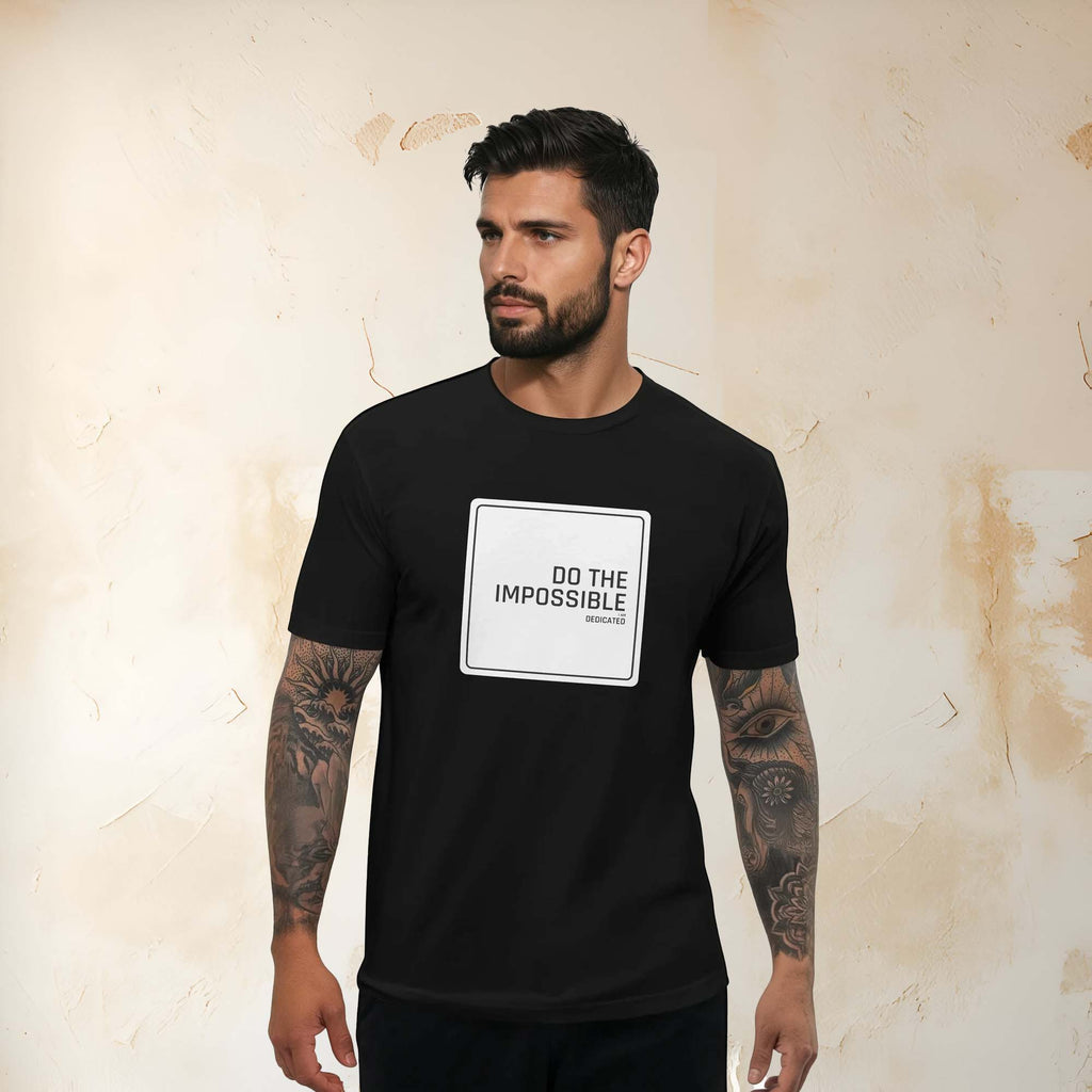 Man wearing black slim-fit t-shirt with "Do the impossible" design, showcasing determination and style.